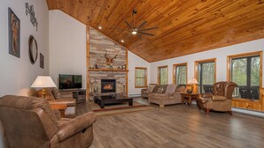 A spacious living room with a fireplace, leather sofas, and a television. - Fairway Breeze by Taylor Made Deep Creek (McHenry)