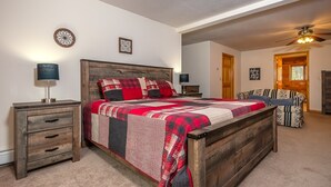 A bedroom with a wooden bed, a nightstand, a dresser, a chair, and a ceiling fan. - Fairway Breeze by Taylor Made Deep Creek (McHenry)