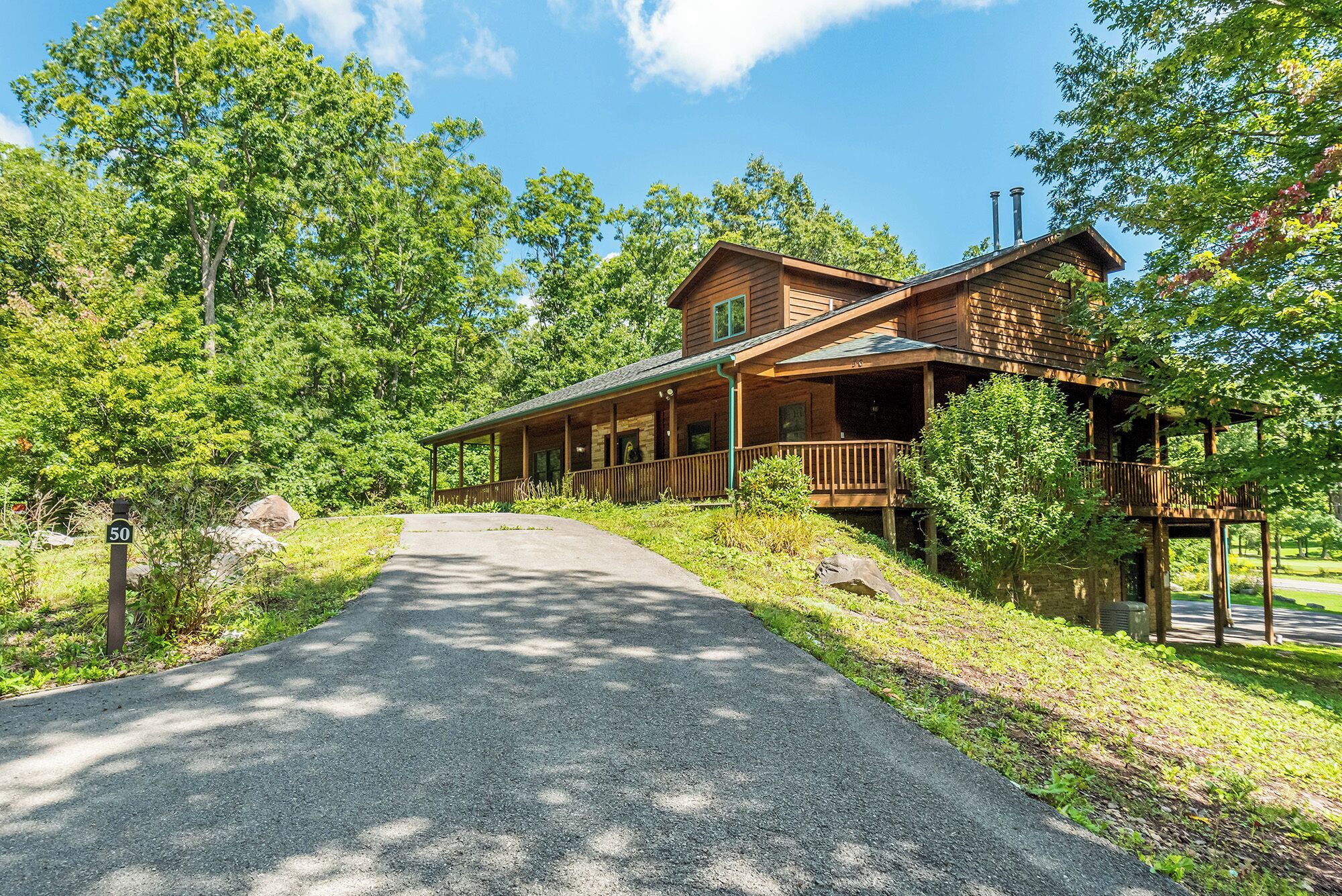 A wooden lodge with a covered porch and a gravel driveway leading to the entrance.