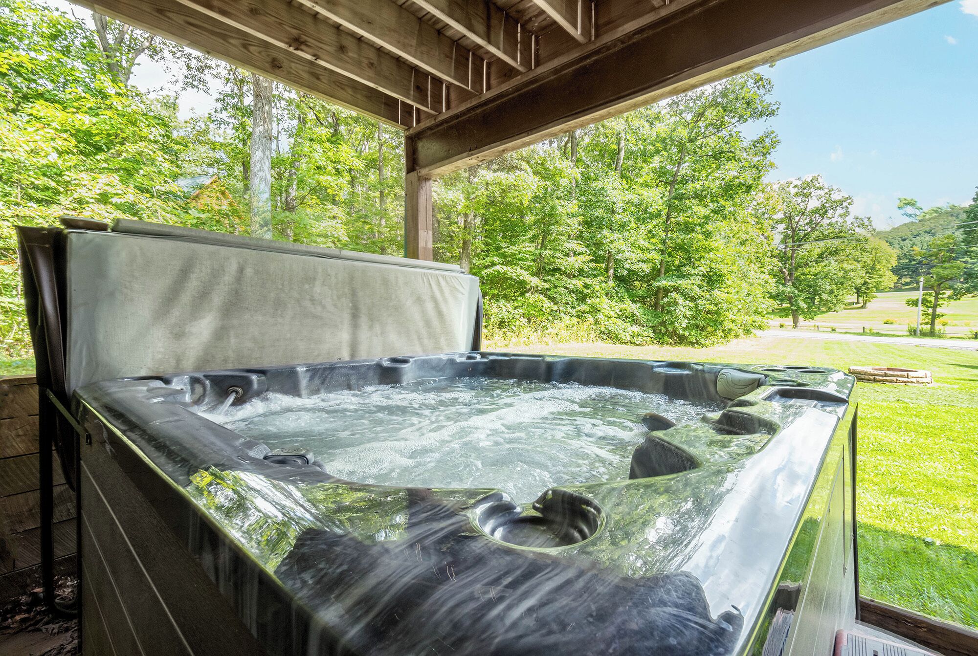 A hot tub with a wooden deck and a view of a lush green landscape.