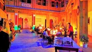 A traditional building with a courtyard, wooden furniture, and people dining.