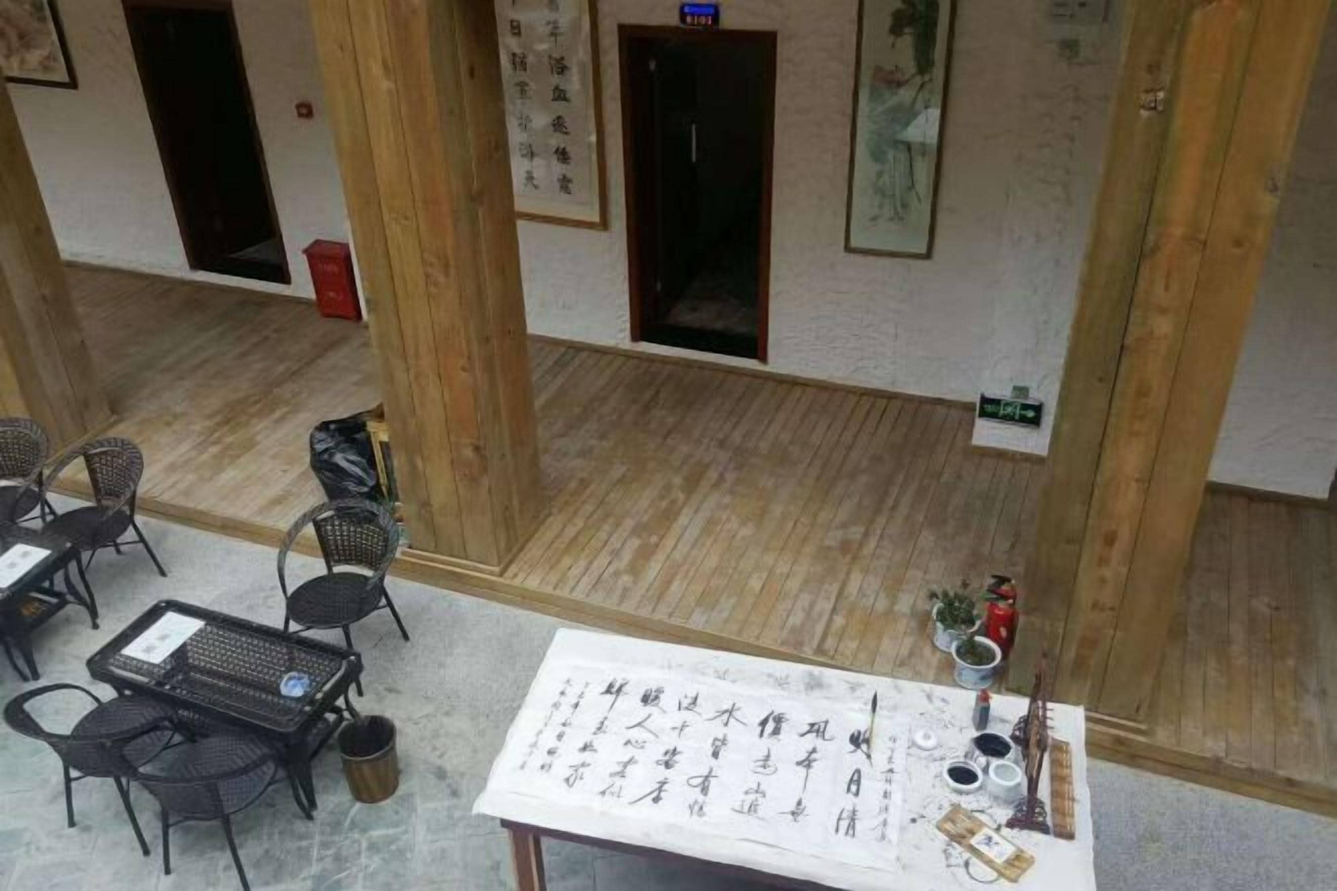 Une pièce avec un plancher en bois, une table avec du matériel d’écriture et des chaises.