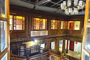 A traditional wooden interior with multiple levels, a staircase, and a chandelier.