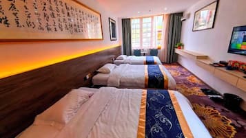 Habitación de hotel con dos camas, televisión, un cuadro grande enmarcado en la pared y ventana con cortinas.