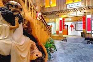 Un interior tradicional con una escalera de madera, una estatua y detalles en rojo.
