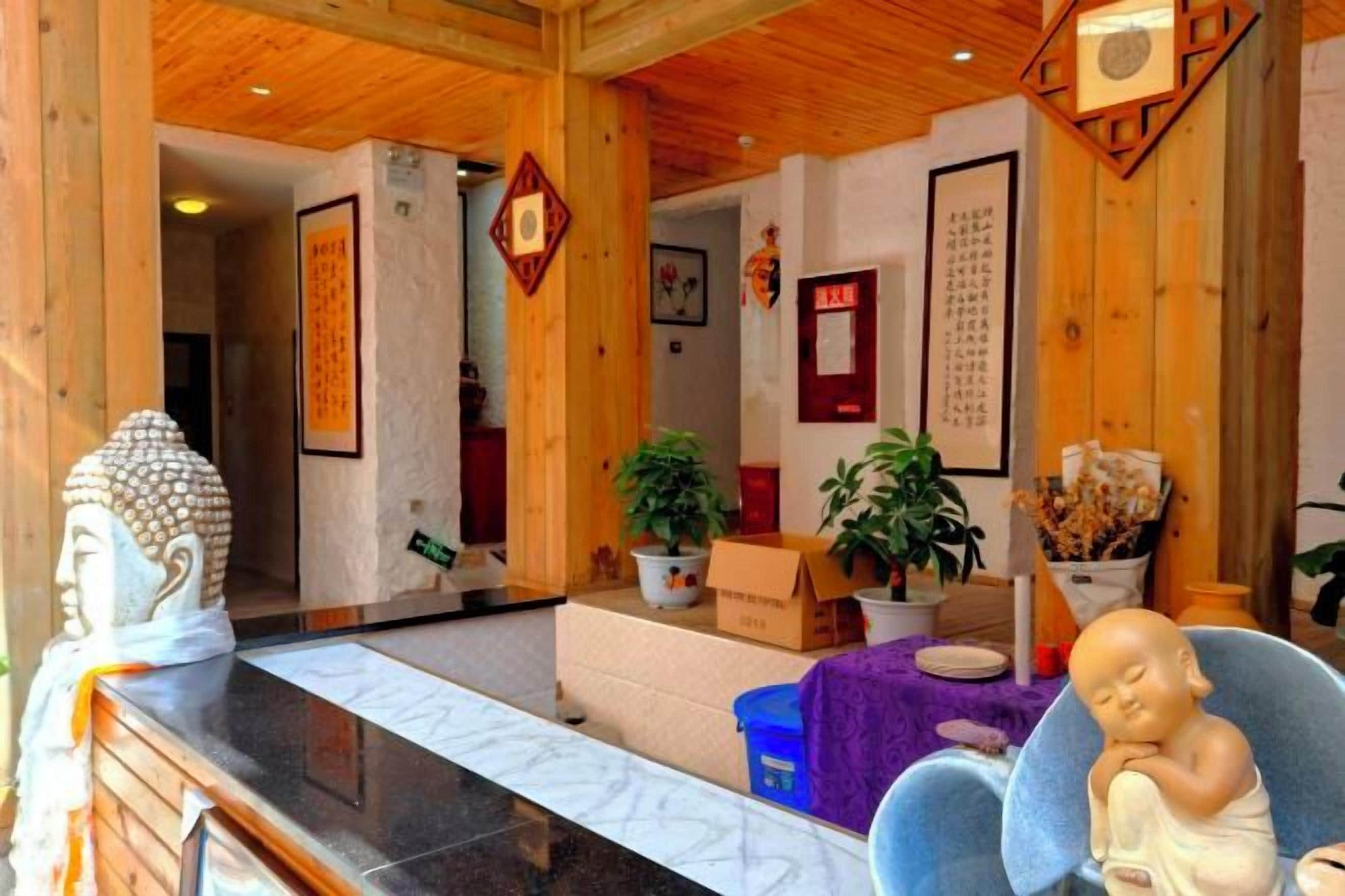 A reception area with a Buddha statue, wooden paneling, and a blue chair.