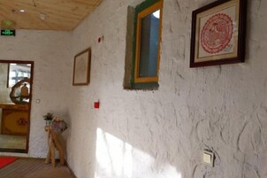 Ein Zimmer mit einer strukturierten weißen Wand, einem gerahmten Bild, einem Fenster mit grünem Rahmen und einer Tür mit roter Fußmatte.