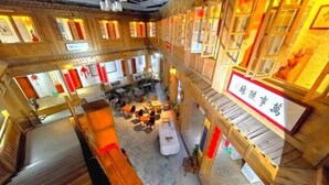 A multi-level hotel lobby with wooden architecture, multiple seating areas, and a staircase.