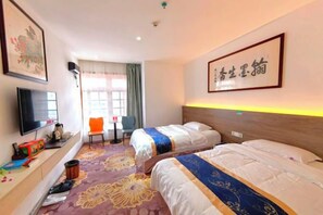 Quarto de hotel com duas camas, televisão, escrivaninha com computador e uma cadeira.