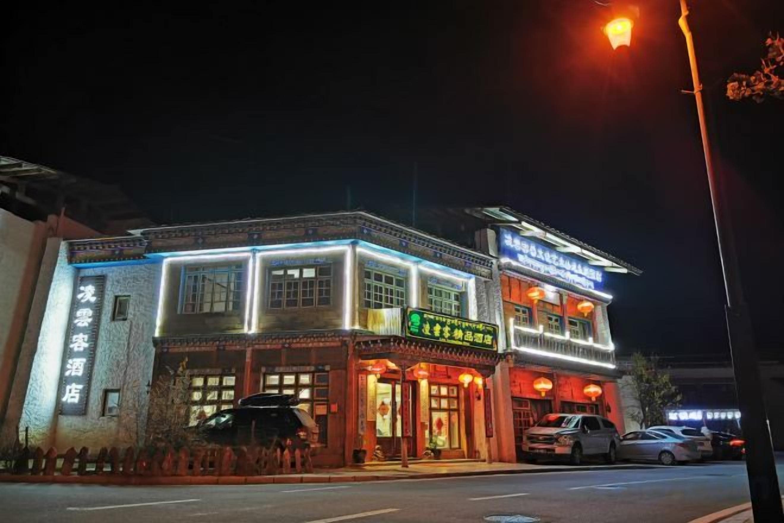 A two-story building with illuminated signage, a visible entrance, and a parked car in front.