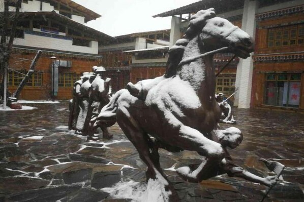 A courtyard with stone flooring and a series of horse statues.