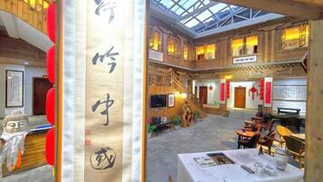A traditional Chinese courtyard with a wooden ceiling, a table set for dining, and a large vertical sign with Chinese characters.