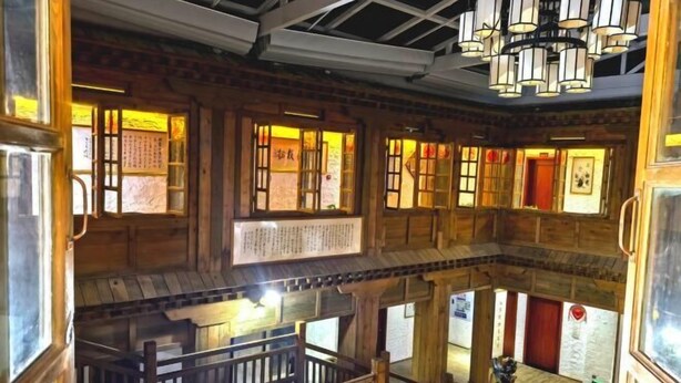 A multi-level wooden interior with traditional Chinese architectural elements, including wooden doors and windows with paper decorations.
