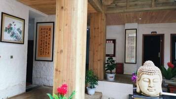 Un intérieur traditionnel avec des poutres en bois, une statue de Bouddha et des calligraphies sur les murs.