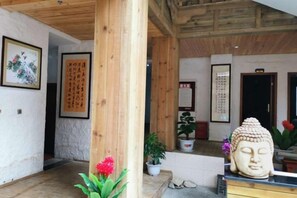 Un interior tradicional con vigas de madera, una estatua de Buda y caligrafía en las paredes.