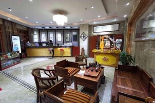 Un hall de hotel con mostrador de recepción, zona de estar y un altar decorativo.