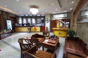 Un hall de hotel con mostrador de recepción, zona de estar y un altar decorativo.