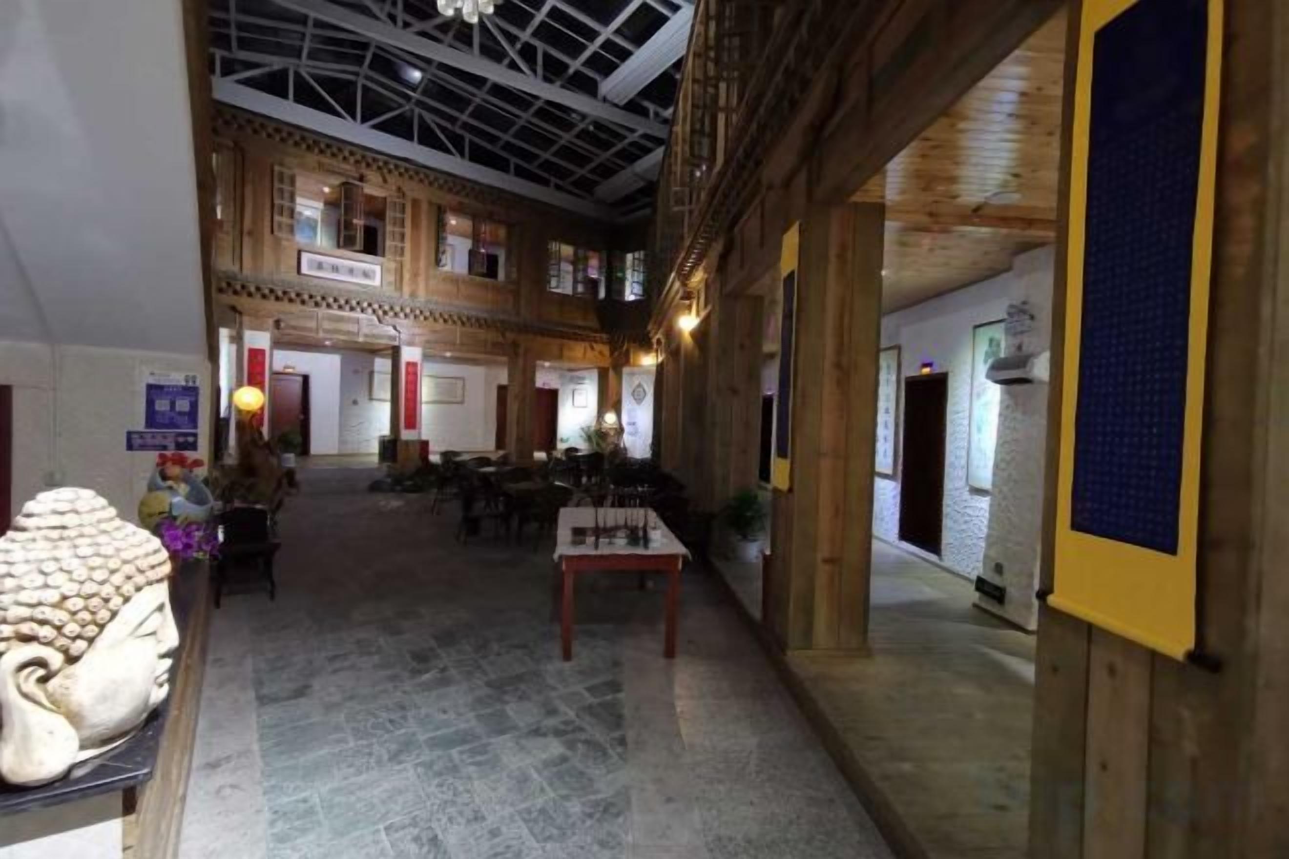 Eine geräumige Lobby mit hoher Decke, Holzbalken und Marmorboden. Tische und Stühle sind zum Sitzen aufgestellt.