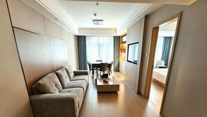 A modern hotel room with a sofa, a dining table, and a TV. - Quanzhou Xingang Hotel (Quanzhou)