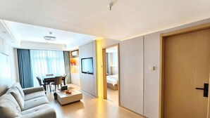 A modern hotel room with a sofa, a dining table, and a TV. - Quanzhou Xingang Hotel (Quanzhou)