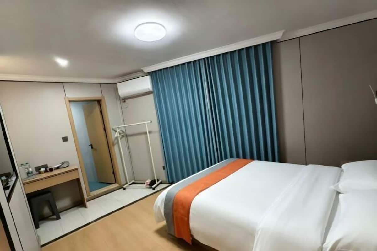Een hotelkamer met een bed, een bureau, een spiegel, een kledingkast en een douche.