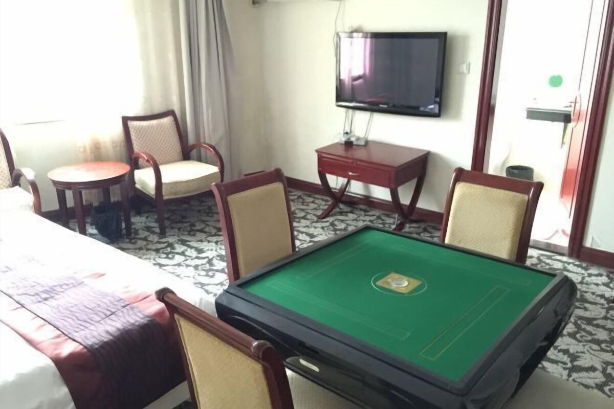 Una habitación de hotel con una mesa de billar, un televisor y un comedor con sillas y una mesa.