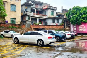 A parking lot with several cars, a building with multiple floors and balconies, and a large tree. - Quanzhou Xingang Hotel (Quanzhou)