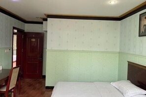 A room with a bed, a wooden chair, and a door. - Hotels Hua Feng (Shangrao)