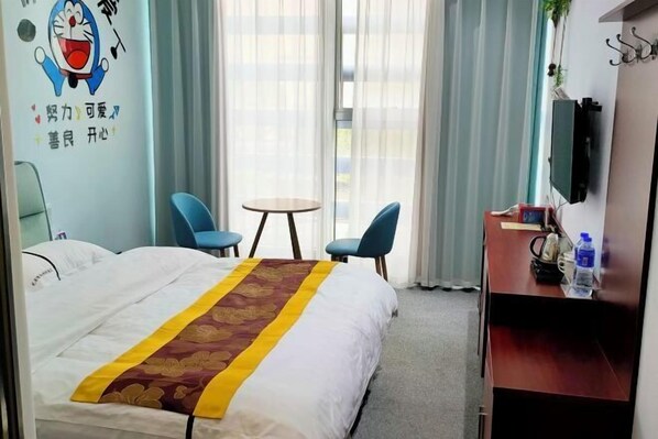 A hotel room with a bed, two chairs, a small table, a TV, and a desk with a water bottle.