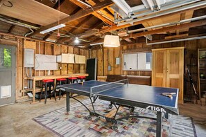 A ping pong table in a rustic room with wooden walls and exposed beams.