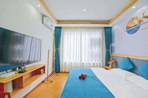 A hotel room with a large flat-screen TV, a bed with a blue quilt, a wooden bedside table, and a wall-mounted artwork. - Lijiang Yihe Light Luxury Homestay (Lijiang Ancient City South Branch) (Lijiang)