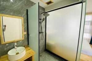 A modern bathroom with a glass shower enclosure, a wooden vanity with a white sink, and a mirror above the sink. - Lijiang Yihe Light Luxury Homestay (Lijiang Ancient City South Branch) (Lijiang)