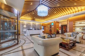 Eine Hotelhalle mit einer Rezeption, einer Sitzecke und einem großen Kronleuchter.