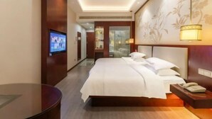 Ein Hotelzimmer mit Bett, Nachttisch, Fernseher und einer Wand mit floralem Dekor.