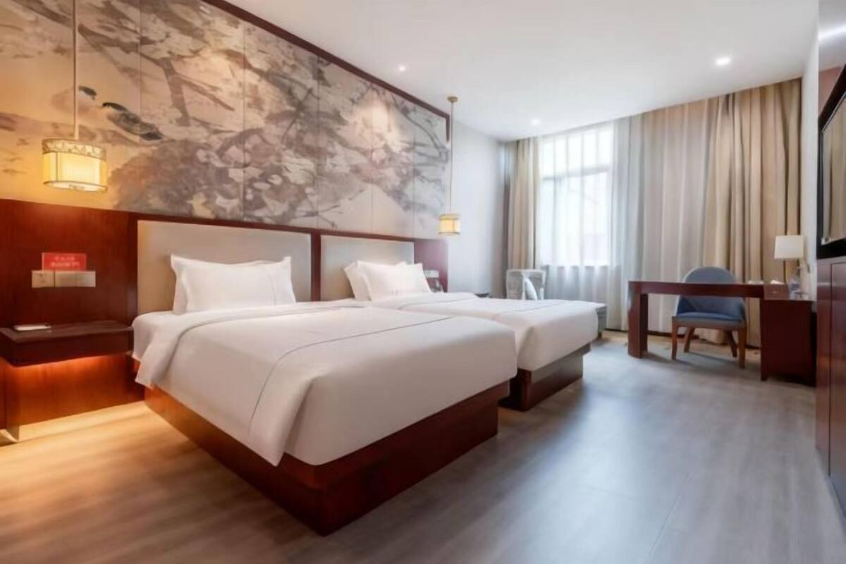 Une chambre d’hôtel avec deux lits, un bureau et une chaise.