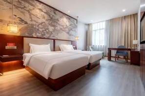 Une chambre d’hôtel avec deux lits, un bureau et une chaise.
