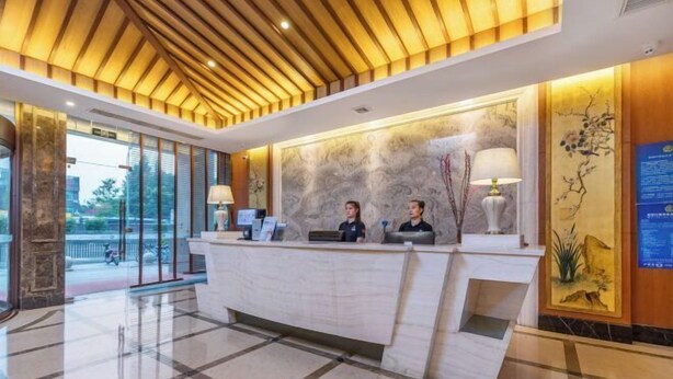 Ein Hotel-Empfangsbereich mit einer Marmor-Rezeption, zwei Rezeptionisten und einem modernen Deckenstil.