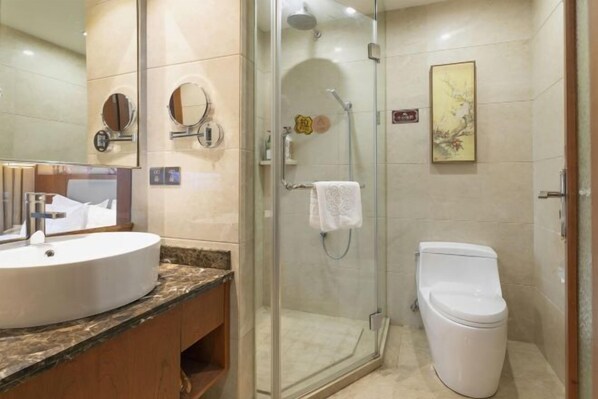 Une salle de bain équipée d’un lavabo, d’un miroir, de toilettes et d’une douche à parois en verre.