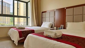 A hotel room with two beds, a large window, and a view of high-rise buildings. - Coconut Maple Home Apartment (Wuzhishan)