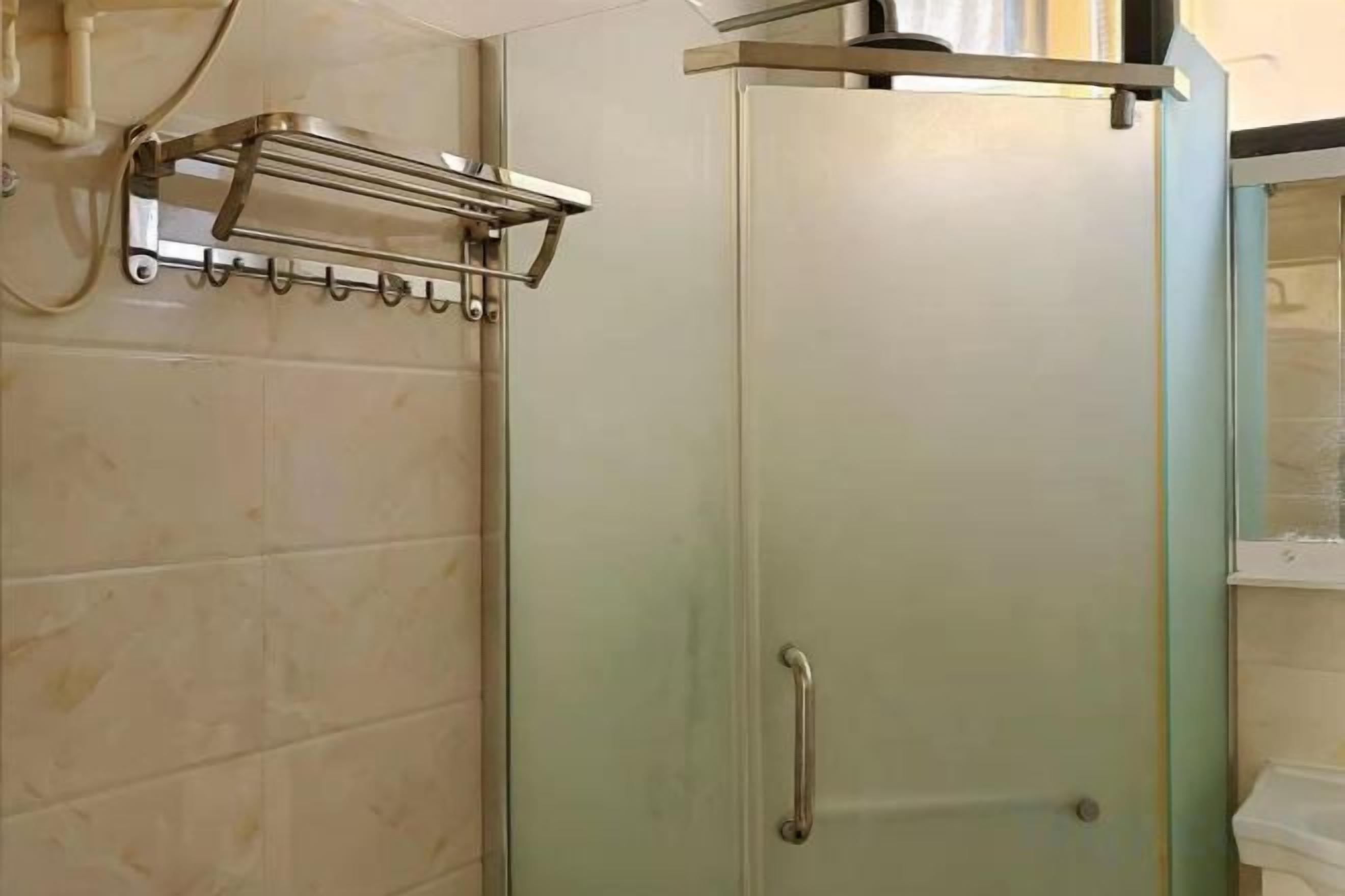 A bathroom with a shower door, a towel rack, and a mirror.