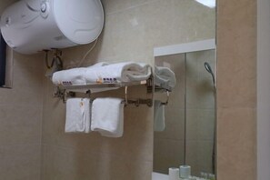 A bathroom with a towel rack holding two towels, a white towel dispenser, and a glass shower enclosure.