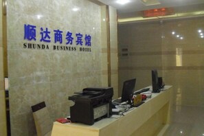A reception desk with a marble wall and a sign reading 'SHUNDA BUSINESS HOTEL'. - Shunda Business Inn (Guangde)