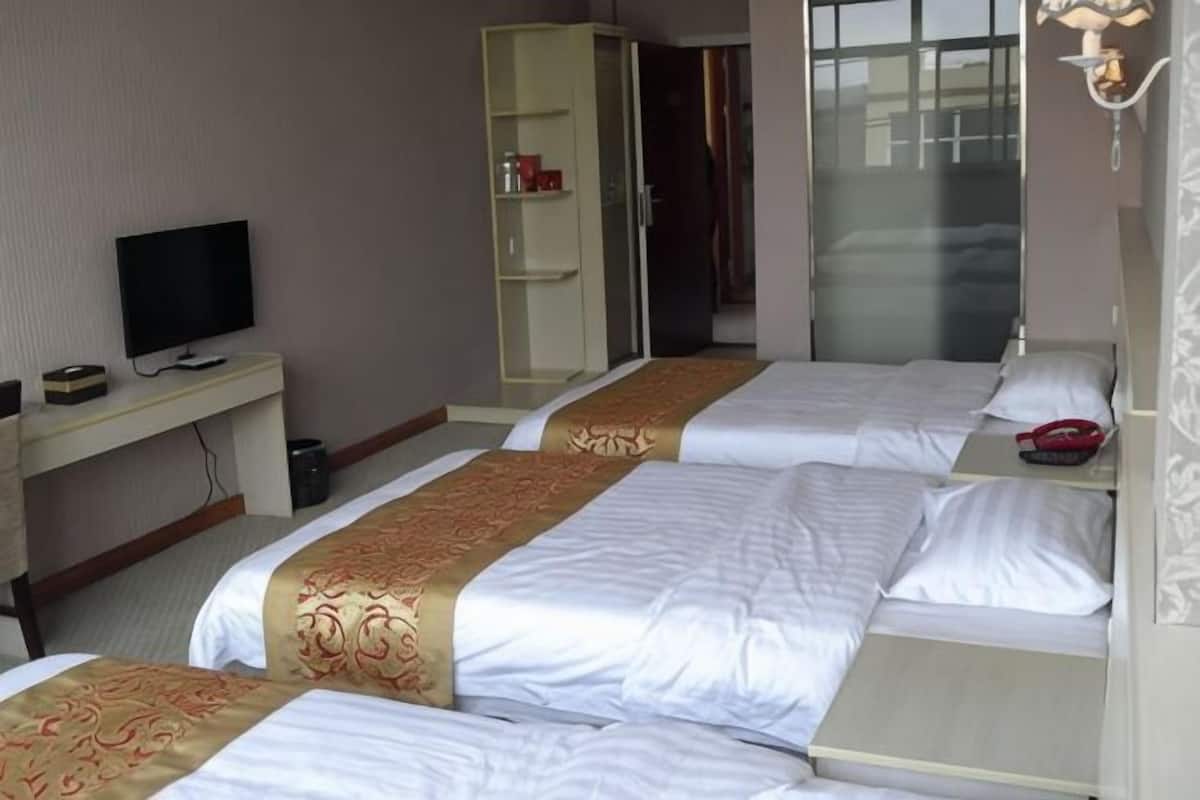 A hotel room with two beds, a TV, a wardrobe, and a desk.
