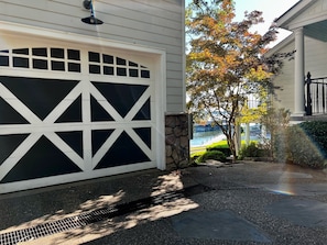 Ett hus med en stor garageport, en stenmur och utsikt över en sjö eller ett annat vattendrag.
