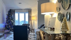 Ein gemütliches Wohnzimmer mit Holzboden, einem Weihnachtsbaum, einer Couch und einem Esstisch mit Lampe.