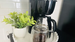 A coffee maker, a glass mug, and a potted plant on a white tray. - Date me ,Top Location , Close Beach  (Greenacres)