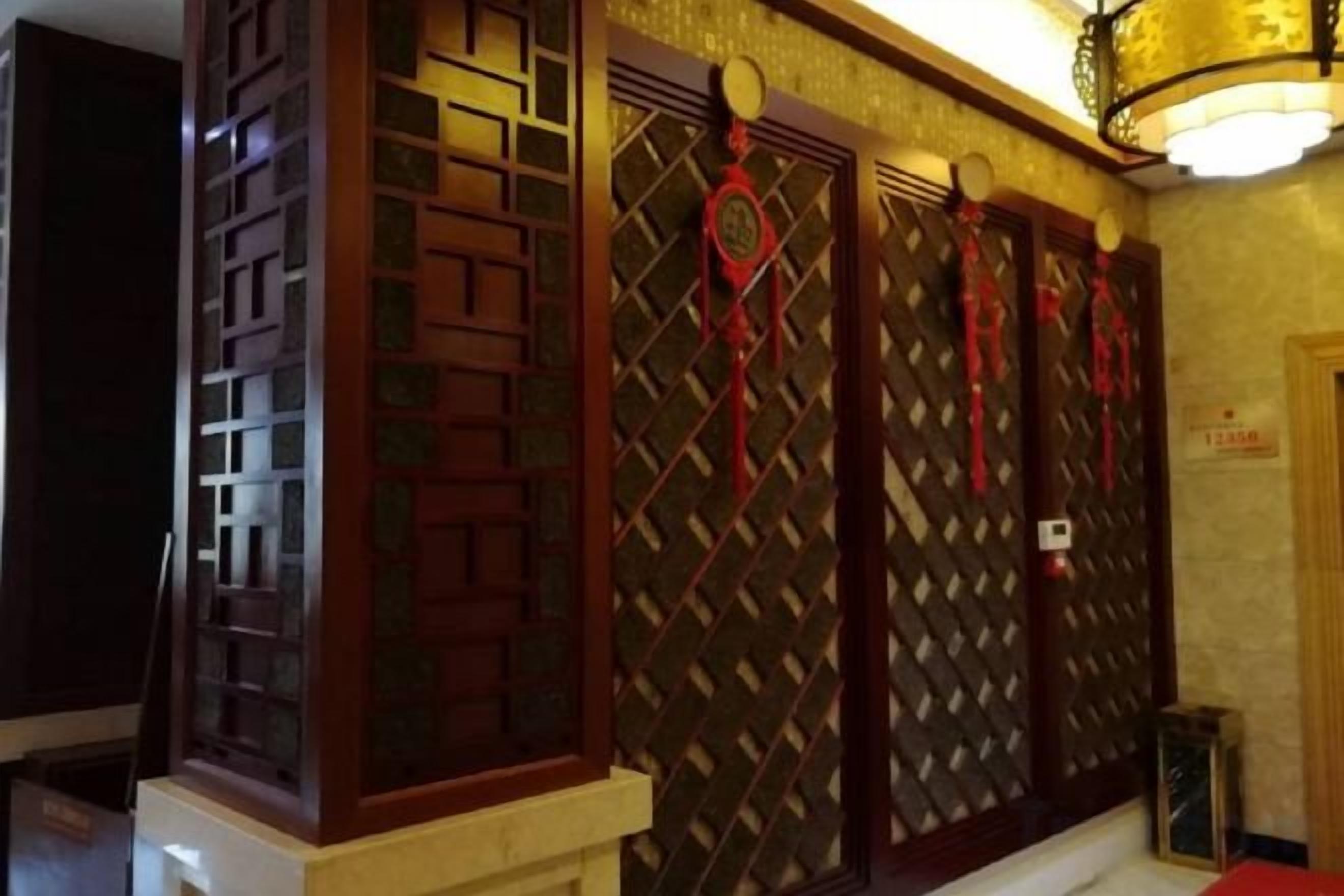 A room with traditional Chinese-style doors, a chandelier, and a red carpet.