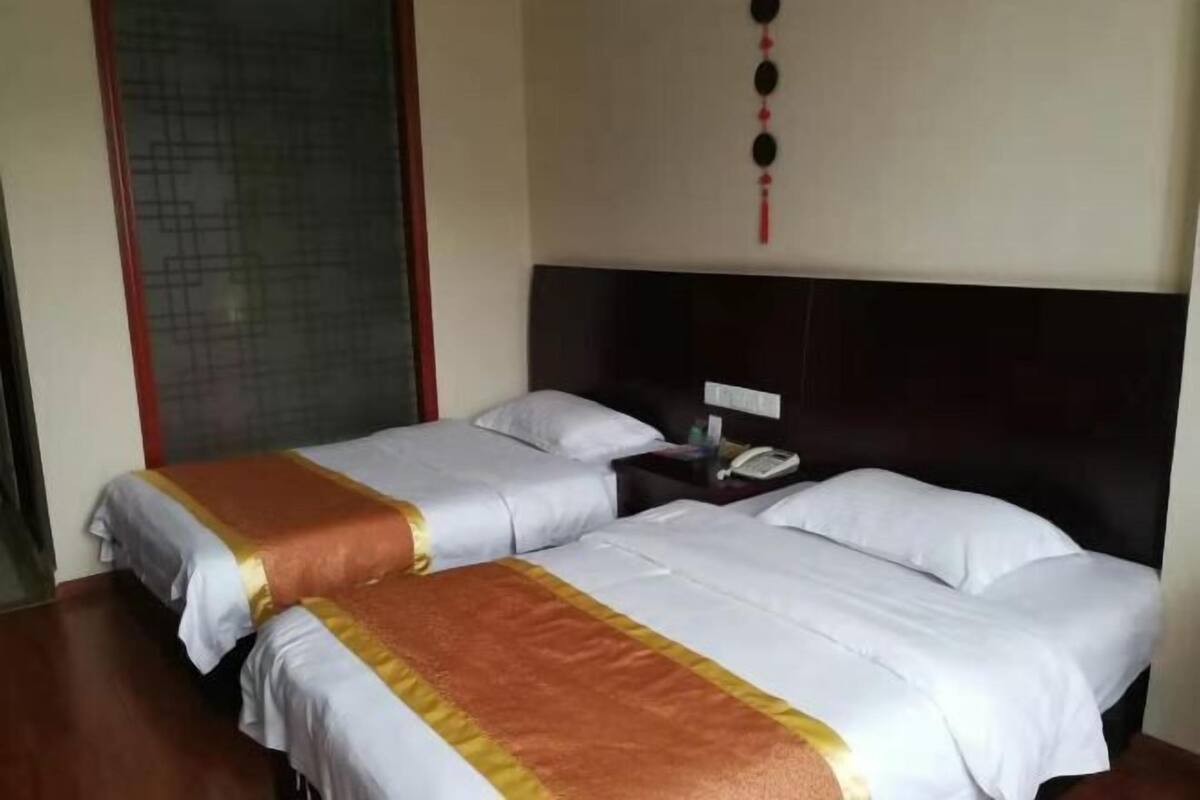 A hotel room with two beds, a nightstand with a phone, and a decorative wall hanging.