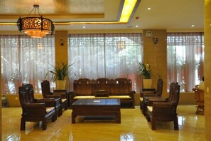 A lobby with a seating area, a coffee table, and large windows with curtains.