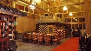 A traditional wooden interior with a central dining area, a staircase, and a checkered floor. - Chaxiang Hotel (Ning'er)